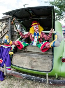 A clown sitting in the trunk of a car