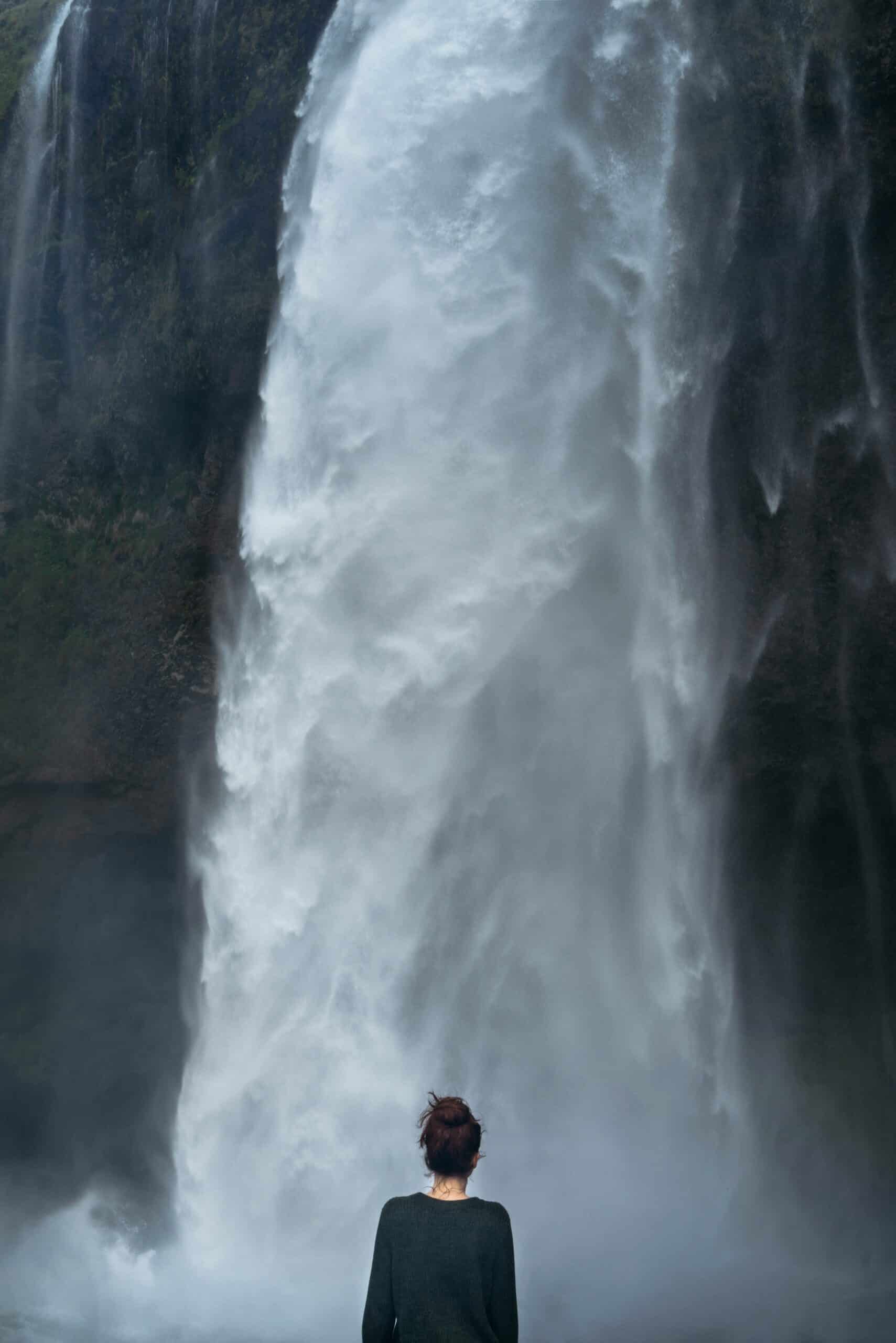 Lady standing in front of a huge waterfall